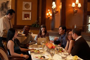 Group of people sitting at restaurant table, waiter serving meal
